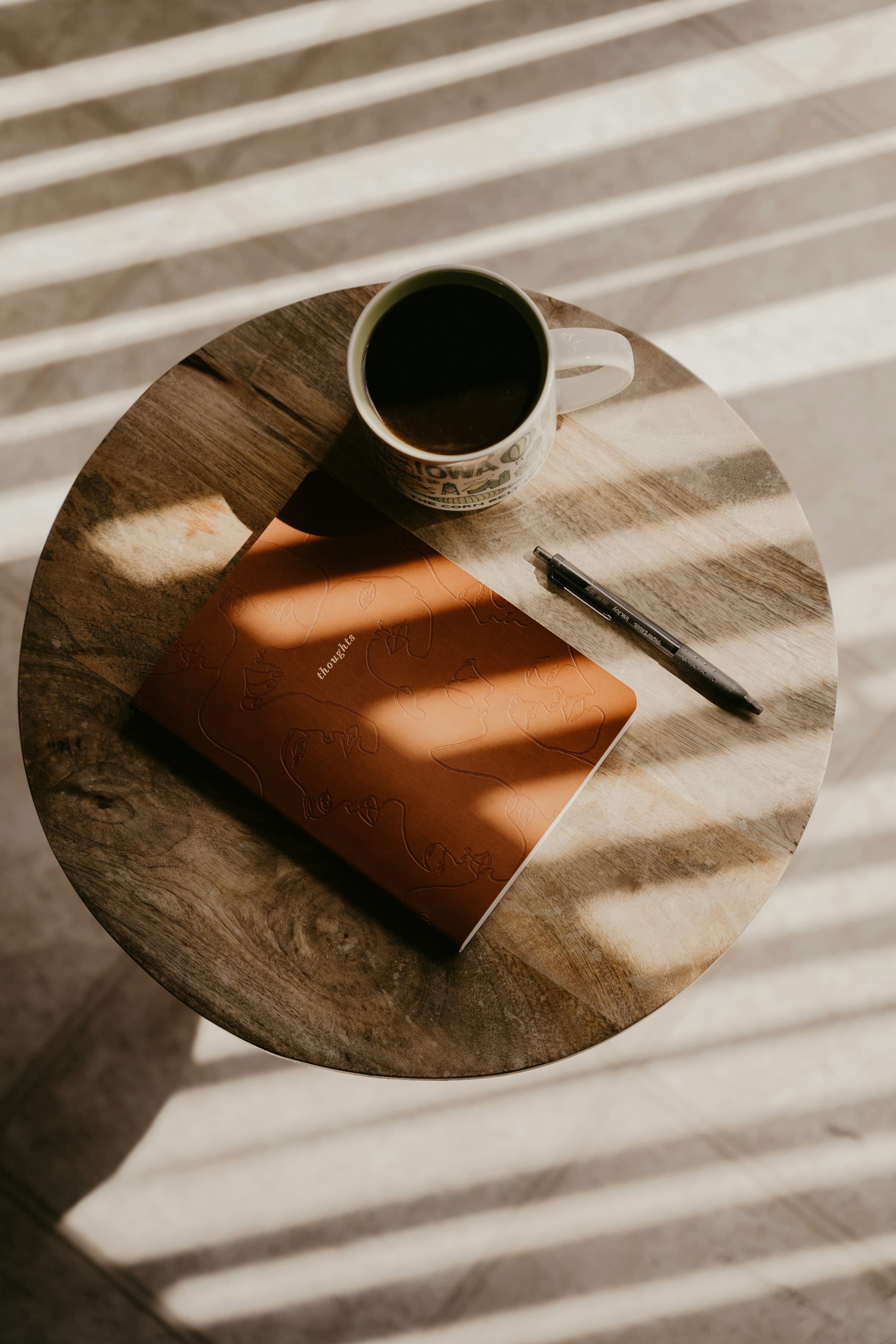A coffee cup beside a notebook in warm morning light